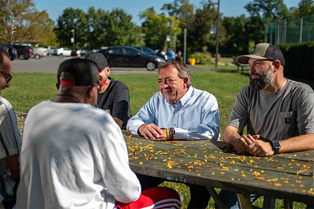 Anthony Verrelli meeting with community members at an outdoor table
